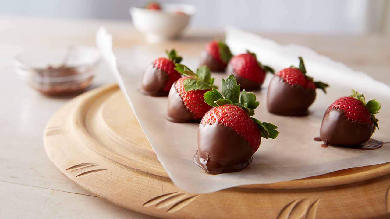 tray of chocolate covered strawberries cooling on parchment paper