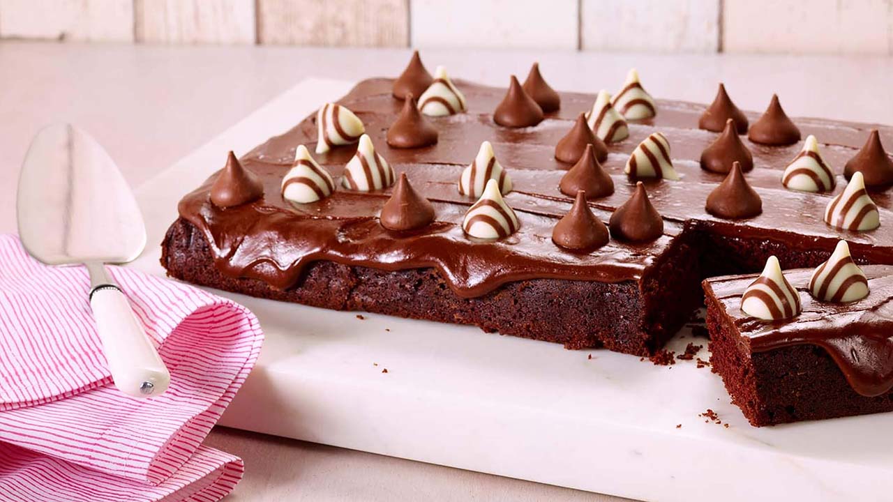 Couper un gâteau au chocolat fraîchement préparé avec des bonbons Hershey's Hugs and Kisses